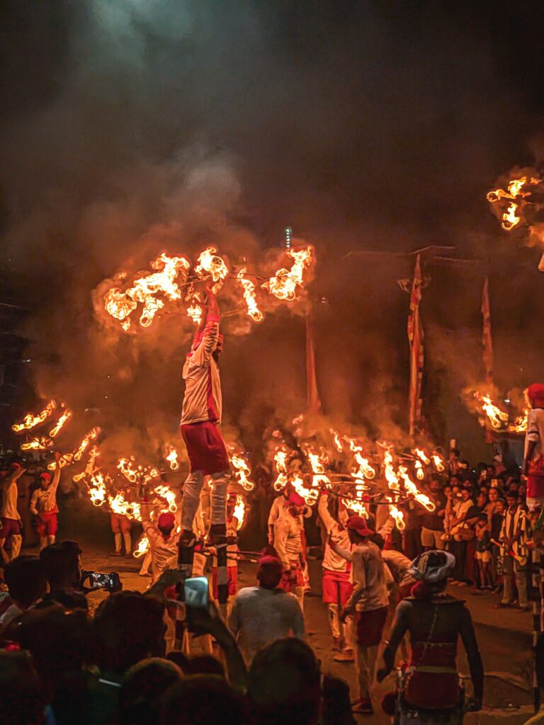 Dynamic fire-ball performers (Ginibolla) during the vibrant night street procession of the Kandy Esala Perahera.